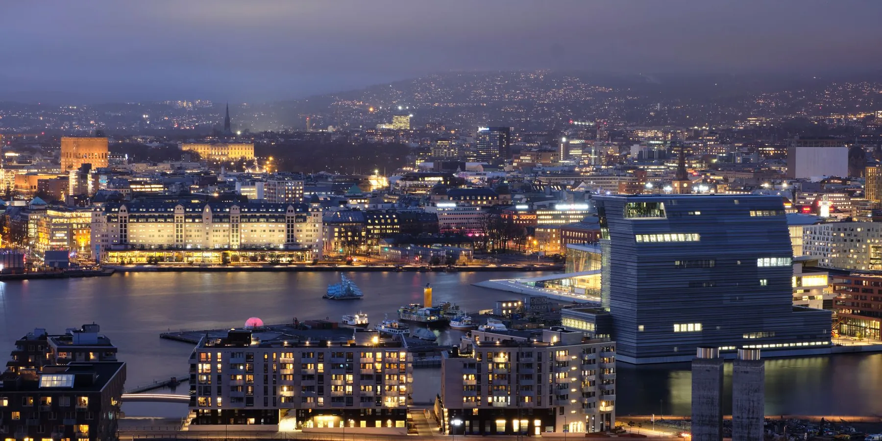 Der Turm des Munch-Museums neben der beleuchteten Osloer Waterfront in der Dämmerung